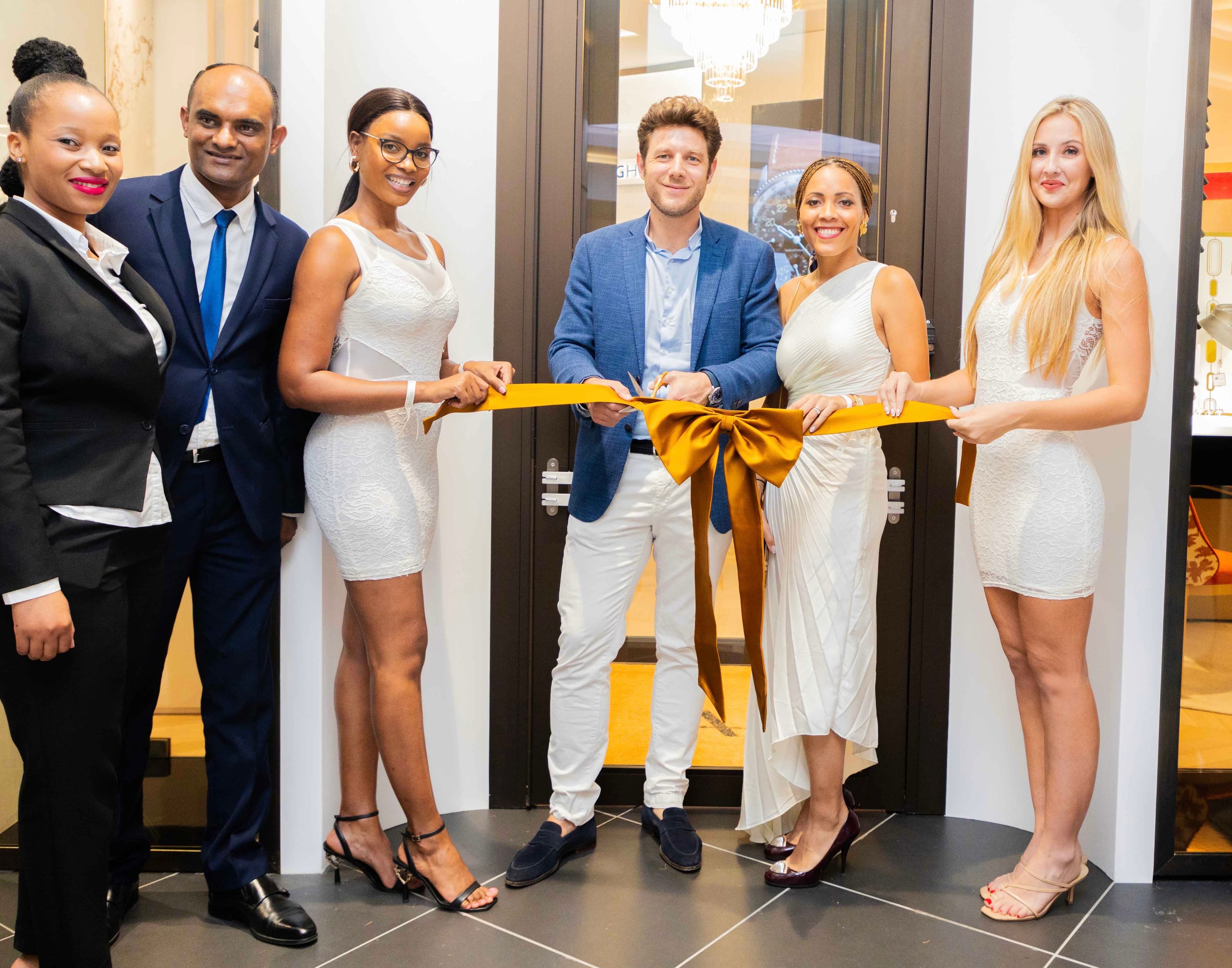 Six guests cutting a gold ribbon at the L’Atelier Paris store launch.